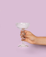 Champagne glass in woman's hand on light background