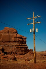 Power line standing next to massive red rock of Southern Utah, vertical shot