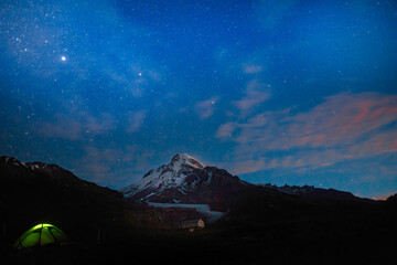 Mountain's snowy peak Kazbek (Kazbegi), Caucasus stands sentinel in the cosmic blue night sky