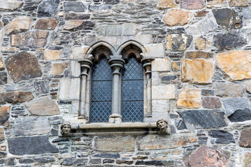 Full frame abstract texture background of an arched stained glass window on a solid medieval era stone wall