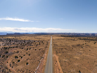 Aerial view of the road towards Canyonlands National Park, Utah, with a car driving by. Bright sunshine