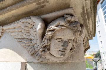 Stone angel head sculpture closeup on monument with intricate wing details, old antique classical...