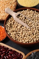 Different types of legumes and cereals on grey table, closeup