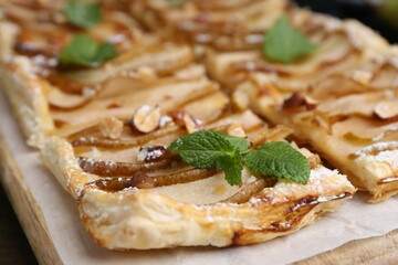 Tasty puff pastry pie with pears and mint on table, closeup