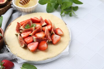 Making galette. Fresh dough, strawberries, figs and mint on white tiled table, closeup. Space for text
