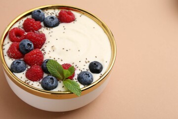 Tasty cooked semolina porridge with berries and mint on pale brown background, closeup. Space for...