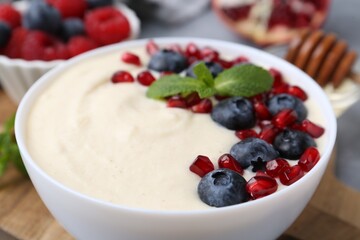 Tasty cooked semolina porridge with blueberries, pomegranate and mint on table, closeup