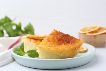 Tasty semolina cake served on white tiled table, closeup
