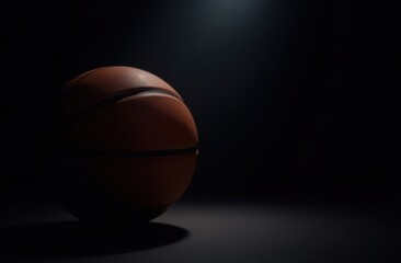Fototapeta premium Basketball ball close-up on dark background under spotlight. Sports and active life concept. Space for text or logo.