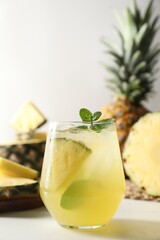 Tasty pineapple cocktail with mint in glass on light table