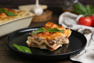 Delicious cooked lasagna with basil on wooden table, closeup