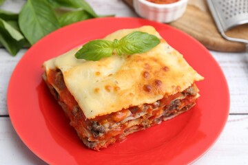 Piece of delicious cooked lasagna with basil on light wooden table, closeup