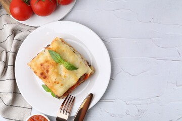 Delicious cooked lasagna with basil served on white textured table, top view. Space for text