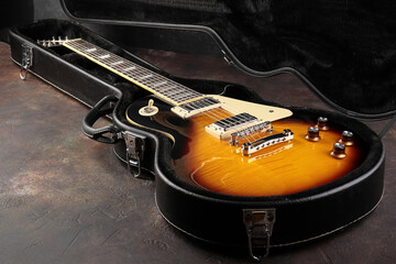 Old electric guitar against the background of a red concrete wall.