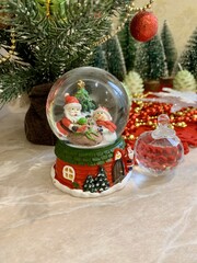 Christmas snow globe with Santa, decorations, and festive background