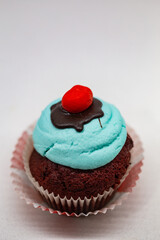 Blue velvet sugar muffin cupcake with red top on a white background
