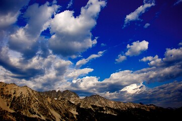 Beautiful, white, puffy clouds scattered across sky over rocky mountains - wide shot