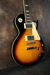 Old electric guitar against the background of a red concrete wall.