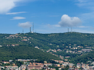 Trieste, Italy - June 27, 2024: Historic San Giusto castle. Looking north on green forested hills above the city under blue cloudscape. 