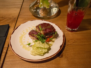 glass of drink and stake on a white plate in the bar of capital kyiv