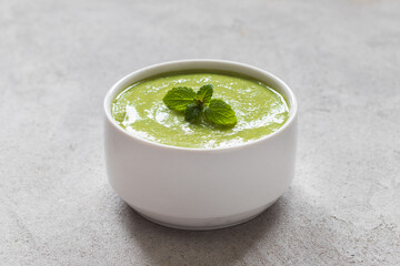 Vegan Pea mint puree soup. In a bowl. On a linen napkin. Light gray background. Close up