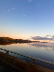 Fall foliage reflected in still river at sunrise from moving car