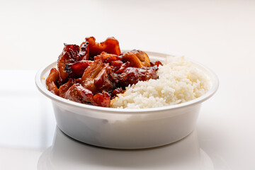 A plastic container holding a takeout Chinese restaurant dish of bourbon chicken served with boiled rice, set against a white background.