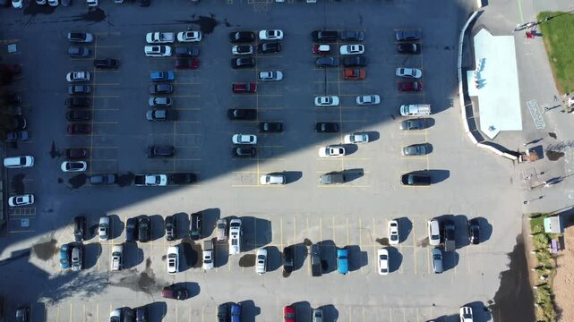 Aerial drone flight parking near big shopping mall in city, car traffic, parking overhead drone top down view, daylight, summer evening sunny weather, lot of cars, busy supermarket car park