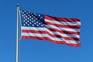 Fototapeta premium American flag waves against clear blue sky in patriotic display