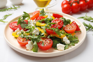 Tasty salad with arugula, cheese and vegetables on white tiled table, closeup