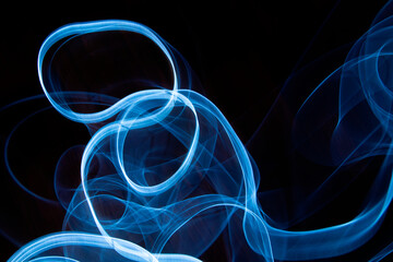 Photography of moving neon light with light trail on dark background, vibrant blue color