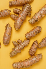 Fresh turmeric roots isolated on yellow background. High resolution photo.
