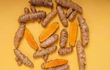 Fresh turmeric roots isolated on yellow background. High resolution photo.