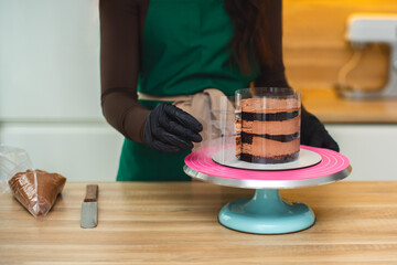 A confectioner removes the transparent packaging from the cake, which she plans to decorate with cream.