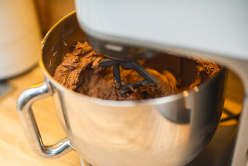 The process of mixing chocolate cream in the chrome bowl of a food processor.