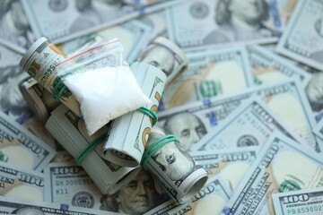 Small cocaine dose in plastic ziplock packet lies on big amount of american currency banknotes