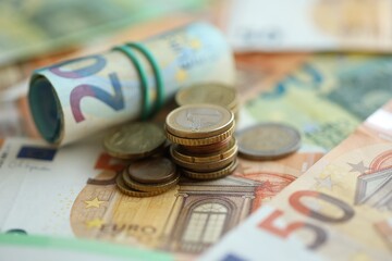 Roll of euro currency money bills and many euro cents on banknotes of european union