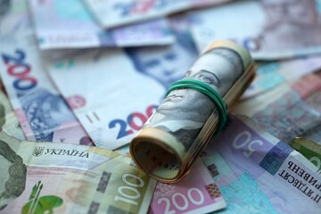 Roll of 500 Ukrainian Hryvnia money bills lies on big pile of ukrainian currency money close up