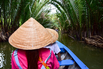 A woman wearing a straw hat is sitting in a boat with a man