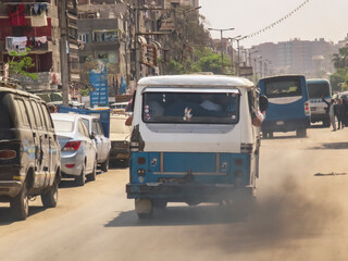 A blue and white van is driving down a street with a lot of traffic