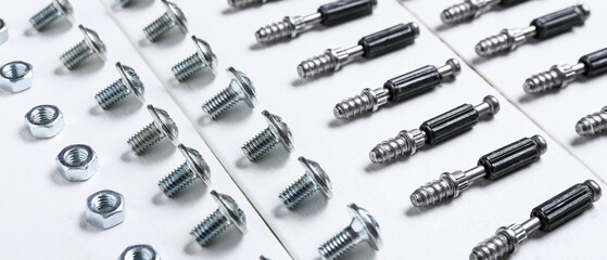 Set of bolts, nuts and dowels on white wooden table, closeup