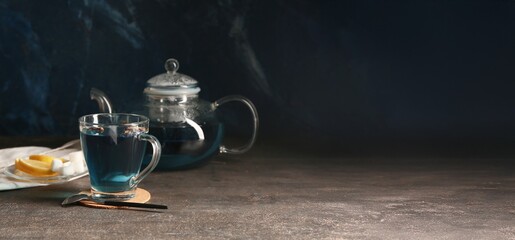 Cup of butterfly pea flower tea on dark background with space for text