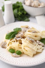Delicious pasta with mushrooms and basil on light table, closeup