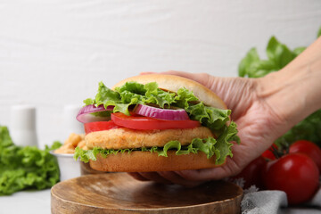 Woman holding vegetarian burger with chickpea cutlet at table, closeup