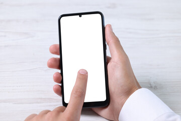 Man unlocking smartphone with fingerprint scanner at light wooden table, closeup