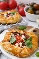 Tasty galettes with tomato, basil and cheese on white table, closeup