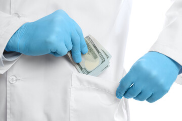 Corruption concept. Doctor putting dollar banknotes into his pocket on white background, closeup