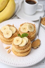 Tasty sandwiches with peanut butter, banana, mint and spoon on table, closeup