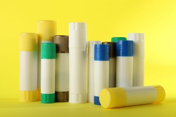 Many different glue sticks on yellow background