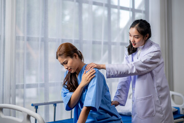 A woman in a blue hospital gown is being helped by a doctor